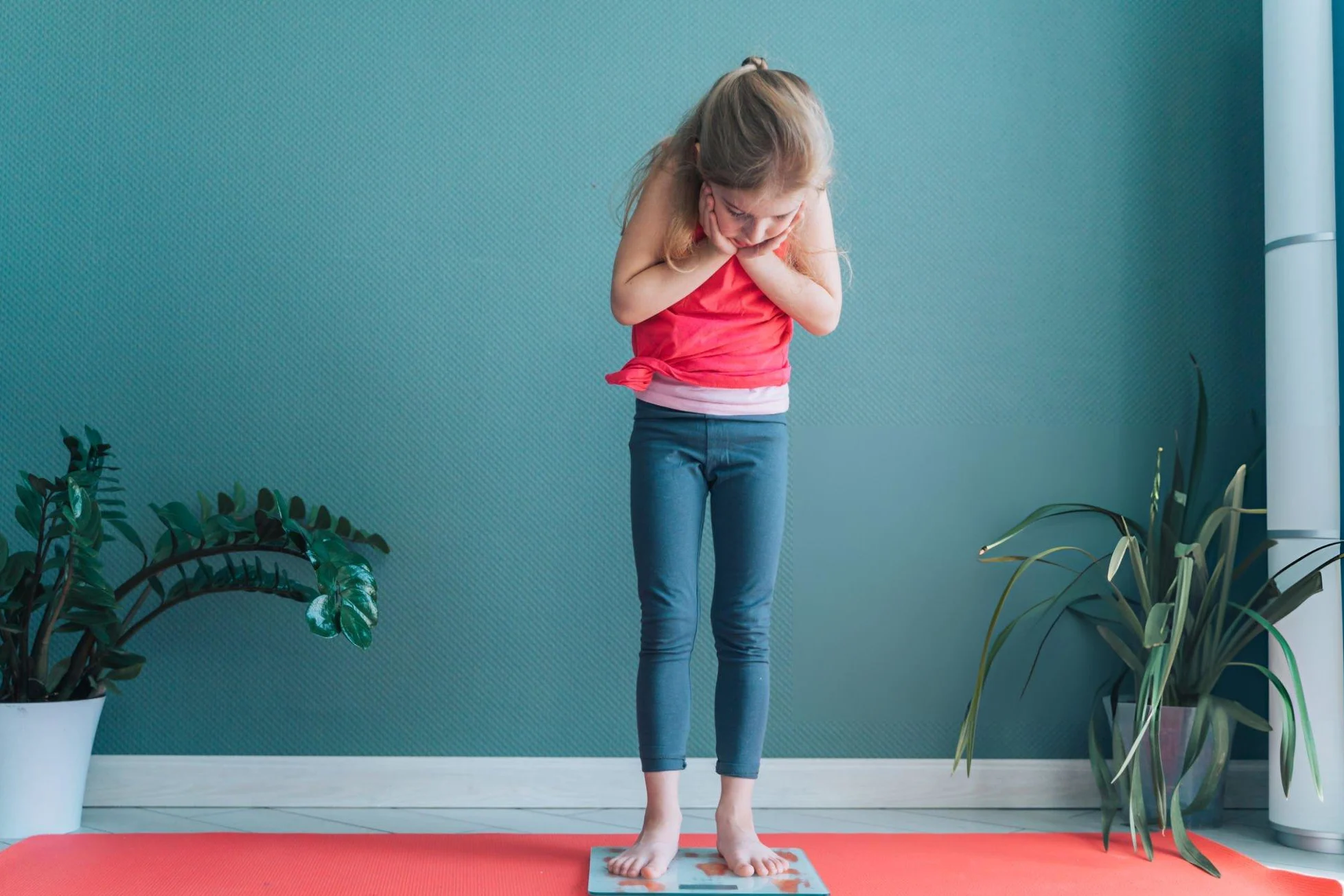 Is BMI interpreted similarly for children, teens, and adults? Cute little barefoot girl standing on weight scale. Holding head in hands. Gain weight