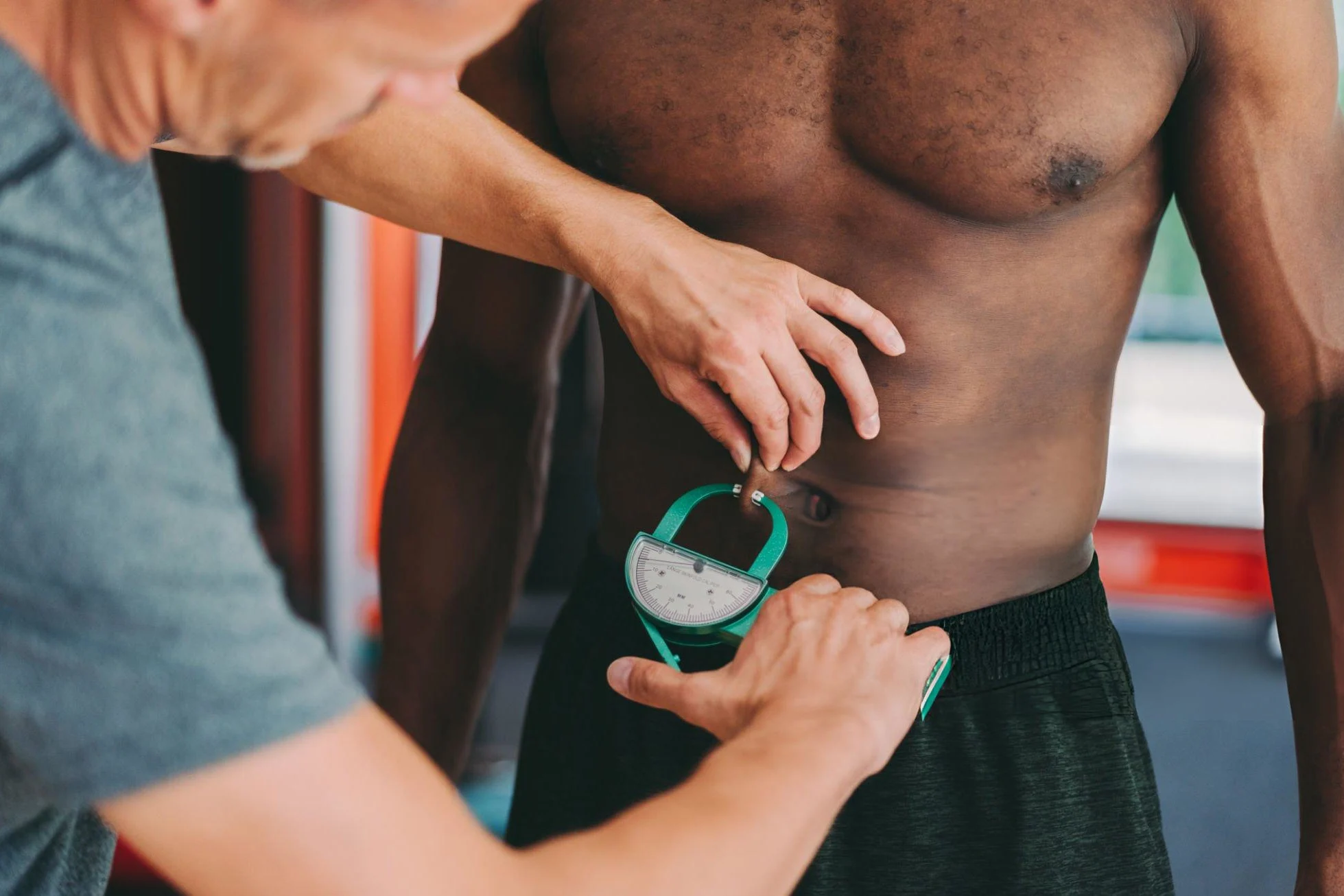 Is BMI Over 25 a Reliable Indicator for Athletes? Personal trainer measuring body fat of sportsman in the gym