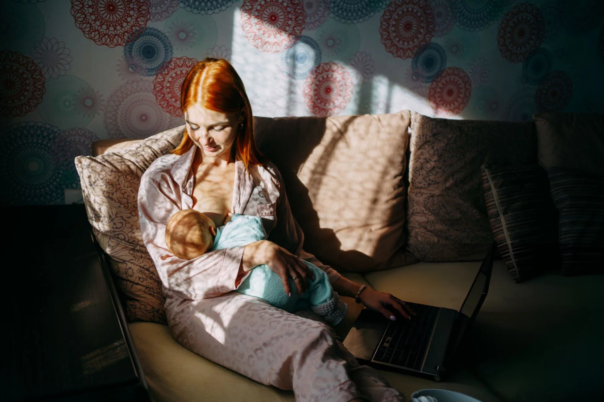 Ultimate 15 Nutrition Tips for Breastfeeding Mothers Mother breastfeeds her newborn son and works remotely with a laptop at home.